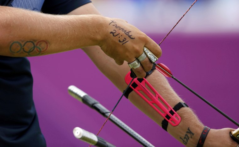 Image: A tattoo of a Bible verse is seen on the hands of Brady Ellison of the U.S. as he prepares to take aim during the men's archery team quaterfinals at the Lords Cricket Ground during the London 2012 Olympics Games