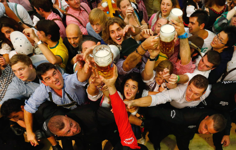Image: Revellers reach out for the first beer in the traditional one-liner \"Masskrug\" beer mugs at  the opening day of the Munich Oktoberfest at the Theresienwiese in Munich