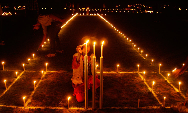 Image: A girl lights candles inside a cricket ground on the eve of Diwali in Allahabad