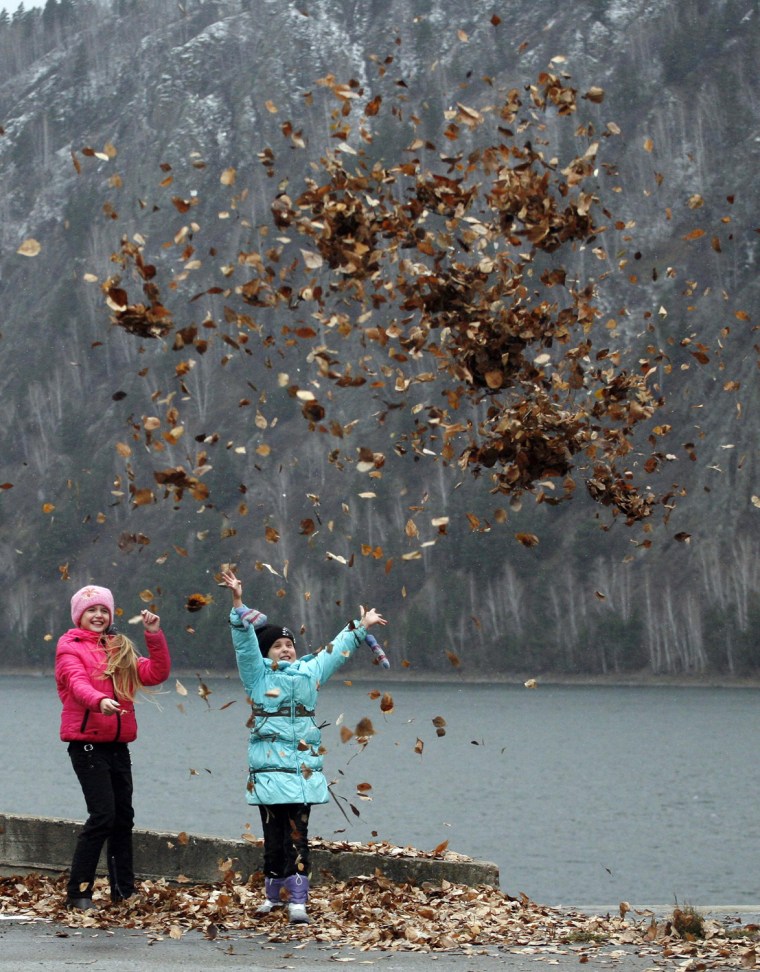 Image: Girls throw autumn leafs in the air on an embankment of the Yenisei River in the Siberian town of Divnogorsk outside Krasnoyarsk