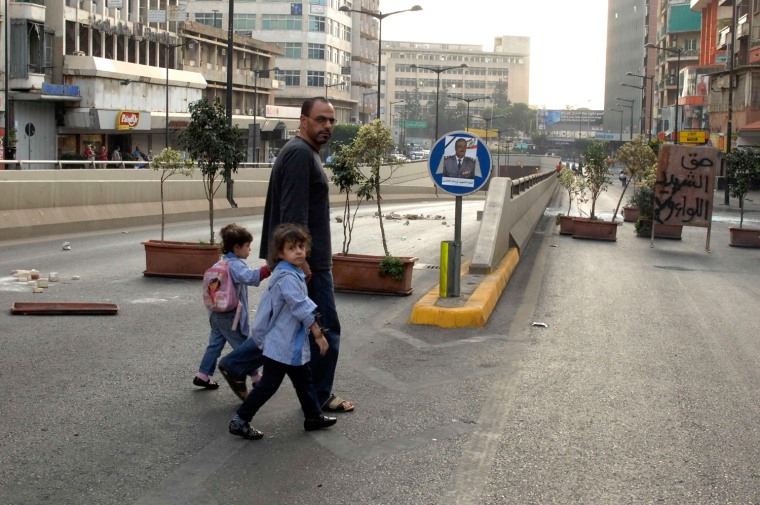 Image: A man and his children walk away from clashes between Sunni Muslim gunmen and members of the Lebanese army in Kaskas, Beirut