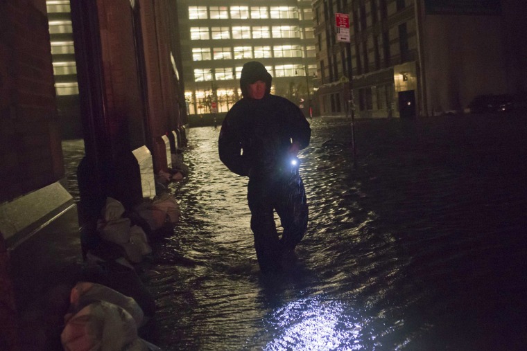 Image: A security guard walks through a flooded street in the financial district of Manhattan