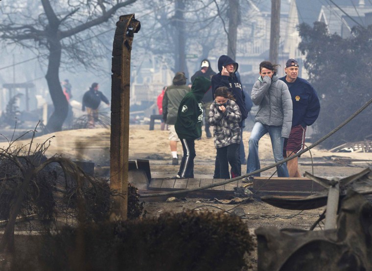 Image: People stand among homes devastated by fire and Hurricane Sandy at the Breezy Point section of the Queens borough of New York
