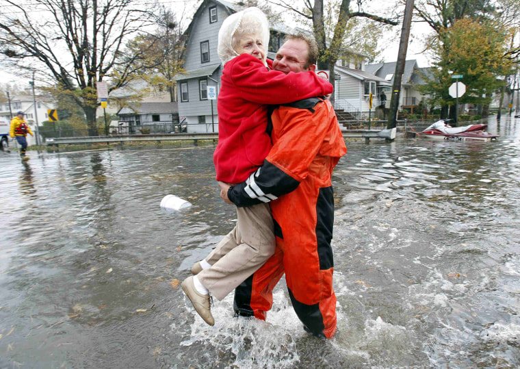 Image: An emergency personnel carries an elderly resident from flood waters brought on by Hurricane Sandy in Little Ferry