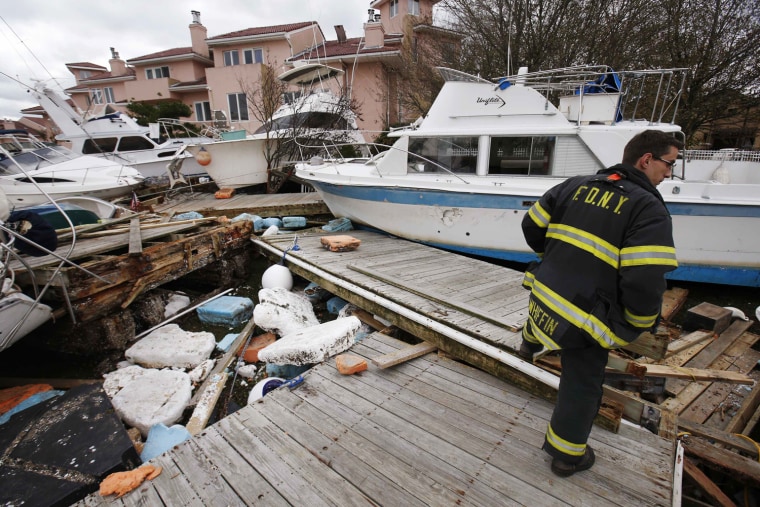 Image: A fire fighter walks amid destroyed boats washed ashore into houses by Hurricane Sandy on Tennyson Drive