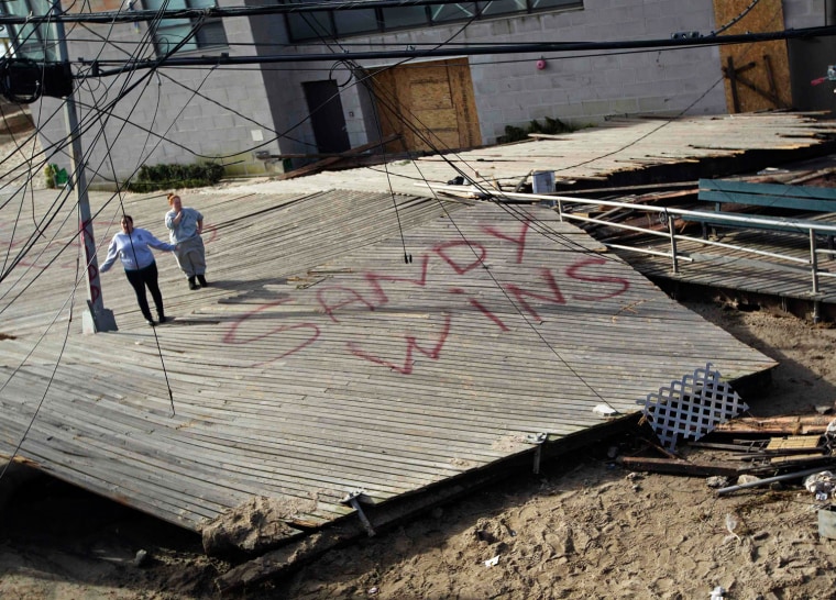 Image: Women stand on a piece of the devastated Rockaway beach boardwalk that was blown onto Beach 91st street in the Queens borough of New York
