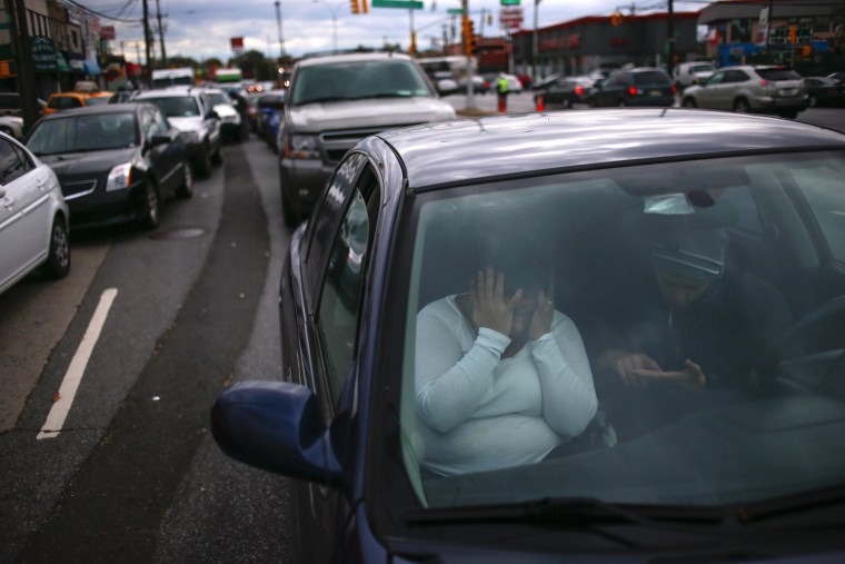 Image: A woman covers her face in frustration while waiting for hours in line to get fuel outside at a gas station in the New York City borough of Queens