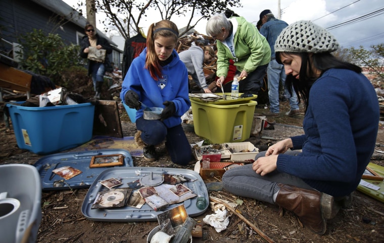 Image: Members of the Traina family sort through photographs and other personal items that they were salvaging from their home which was completely destroyed by flood water storm surge from Hurricane Sandy in New York