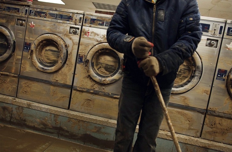 Image: Liu uses a broom to clean up mud and water from extensive flooding in a laundromat due to superstorm Sandy in Coney Island