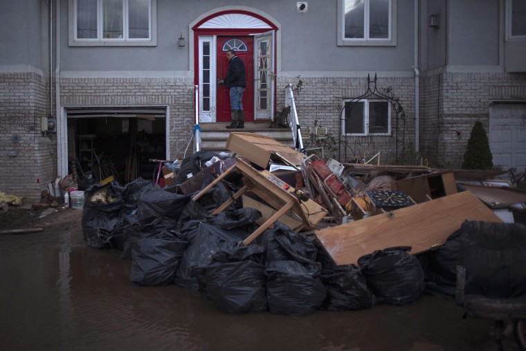 Image: A man stands outside his house which was left flooded by hurricane Sandy in Staten Island borough of New York