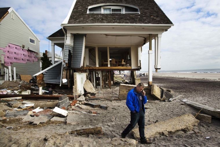 Image: Homeowner Rob Ostrander talks on the phone in front of his Hurricane Sandy damaged home in the Brooklyn borough region of Belle Harbor in New York