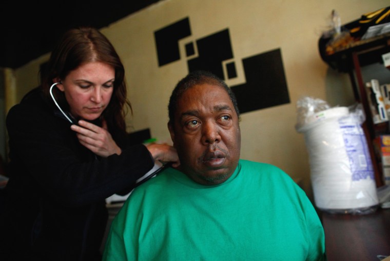 Image: A volunteer checks Donald Vaughn in his apartment at a public housing facility in the Rockaway section of Queens