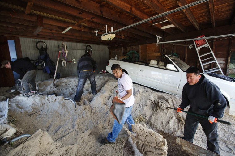Image: Contractors work to dig several feet of sand out of a garage after it was deposited by the storm surge of superstorm Sandy in the town of Mantoloking