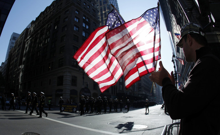 Image: A man holds up American flags during the Veterans Day Parade in New York