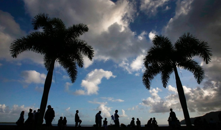 Image: Tourists look to the sky as clouds obscure a full solar eclipse in the northern Australian city of Cairns