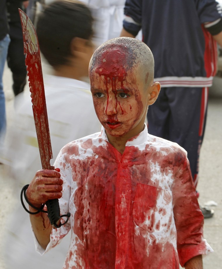 Image: An Iraqi Shi'ite Muslim child gashes his forehead with a sword during a ceremony marking Ashura in Baghdad