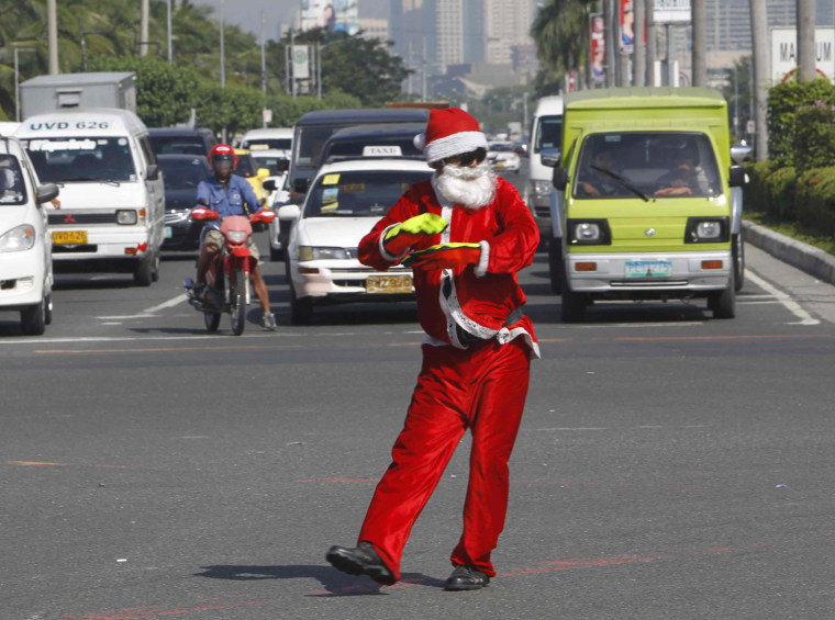 Image: Traffic enforcer, wears a Santa Claus costume as he directs traffic along a main street in Pasay city, metro Manila