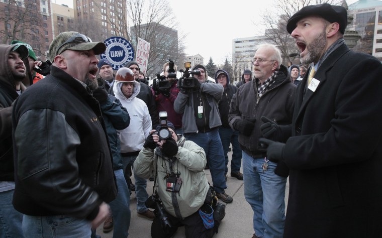 Image: An anti right-to-work protester and a pro right-to-work protestor yell at each other outside of Michigan's state capitol building in Lansing
