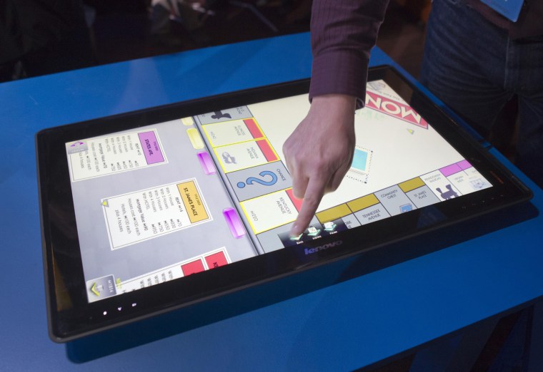 Image: A man tries out a Monopoly game on a Lenovo's IdeaCentre Horizon Table PC during an Intel news conference at the CES in Las Vegas