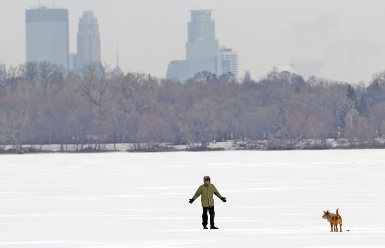 Image: Man walks dog across lake during cold weather in Minneapolis