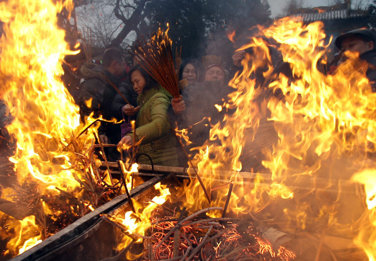 Image: People burn incense to pray for good fortune at Yonghegong Lama Temple in Beijing