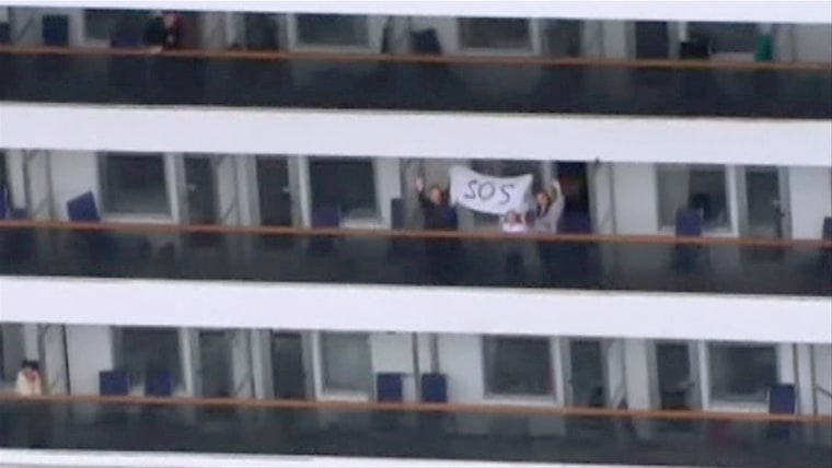 Image: People wave and hold an SOS sign at the side of their balconies on the cruise ship Carnival Triumph cruise ship, off the coast of Alabama
