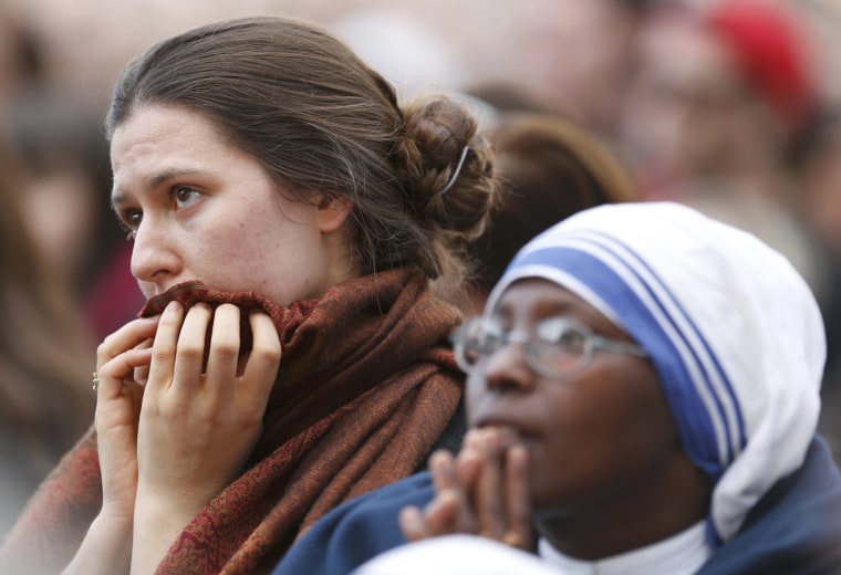 Image: People react near a giant screen showing the departure of Pope Benedict XVI  from the Vatican City