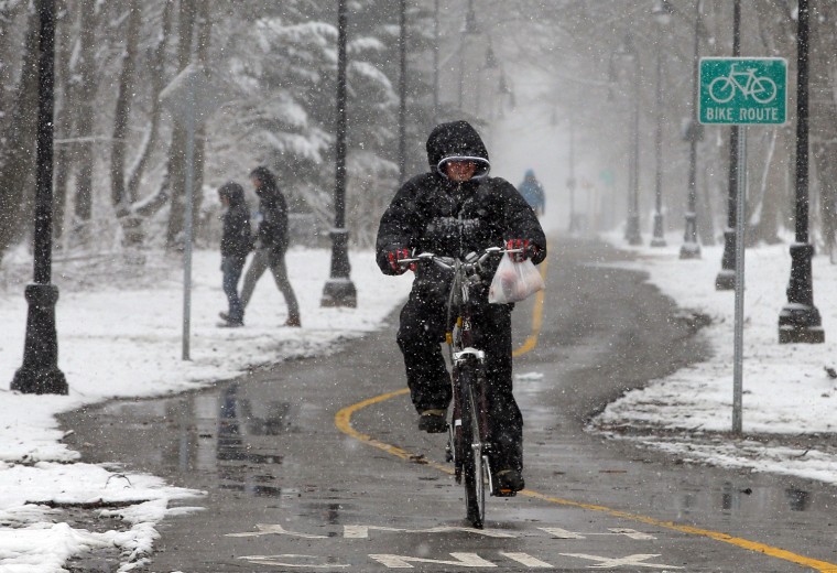 Image: A bicyclist rides through the snow at the beginning of a winter storm in Somerville
