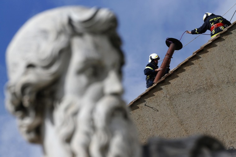 Image: Members of the fire and rescue service set a chimney on the roof of the Sistine Chapel at the Vatican