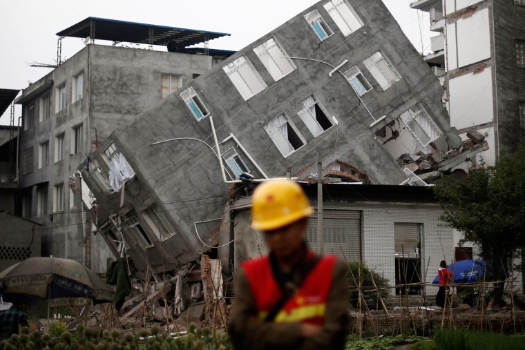 Image: A rescuer walks in front of a damaged building after Saturday's earthquake in Lingguan town of Baoxing county, Sichuan province