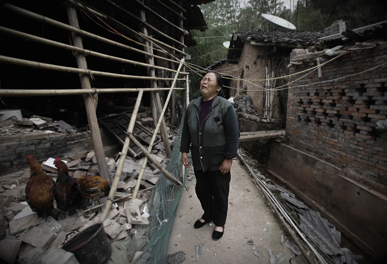 Image: A woman cries amongst collapsed houses in Ya'an