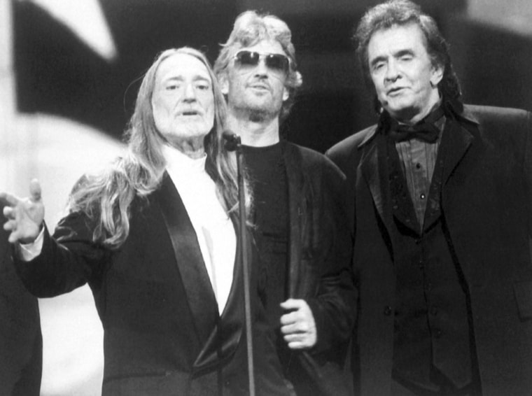 Willie Nelson gives a thank-you speech along side Kris Kristofferson and Johnny Cash (right) for his induction into the Country Music Hall of Fame during the Country Music Association Awards at the Grand Ole Opry House in Nashville, Sep. 29, 1993. (AP Photo)