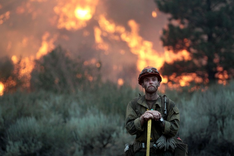 Image: A  firefighter with the Idaho City Hotshots looks for spot fires during a back burn along the Pine-Featherville Road while battling the more than 90,000-acre Elk Fire
