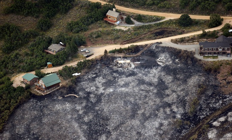 Image: Untouched homes next to the ashes of a home and blackened foliage near Rockport, Utah