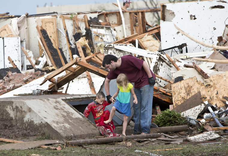 Image: A man and two children walk through debris after a huge tornado struck Moore, Oklahoma