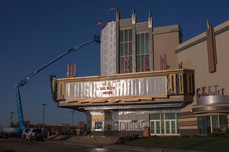 Image: A sign reads \"God Bless Moore\" as workers make repairs to the Warren theatre after the Oklahoma City suburb of Moore, Oklahoma which was left devastated by a tornado