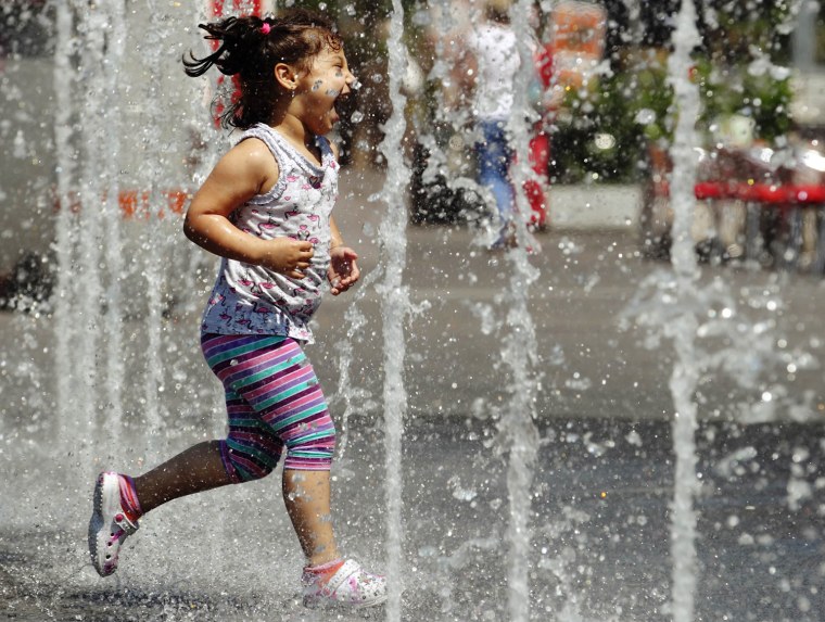 Image: A girl runs through water fountains at a public square in Vienna