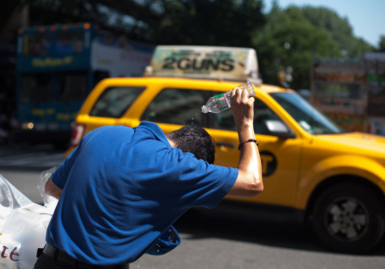 Image: A man pours water on his head to cool off during hot weather in midtown Manhattan.