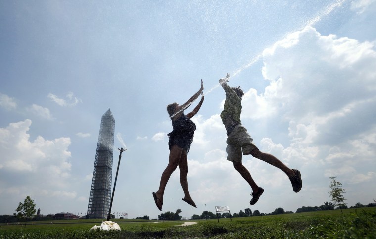 Image: Friends \"high ten\" in a sprinkler on a unusually hot day in Washington