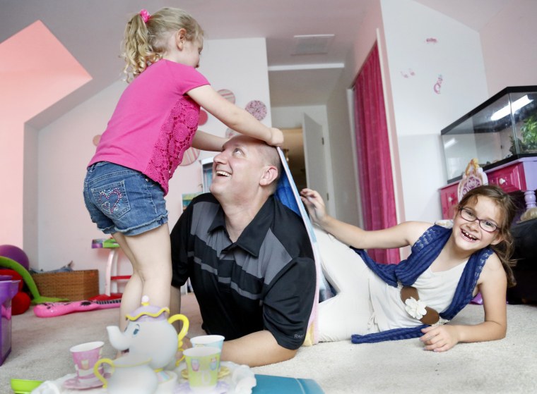 Carl Poff plays with his two daughters Joselyn, left, and Jillian in their playroom after have a tea party. Poff works as a prison guard on the weekends, and takes care of his daughters in his spare time.