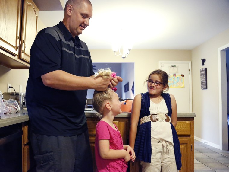 Carl Poff helps his daughter Joselyn put her hair in a ponytail after a fun playtime around the house before they get ready to start making dinner.