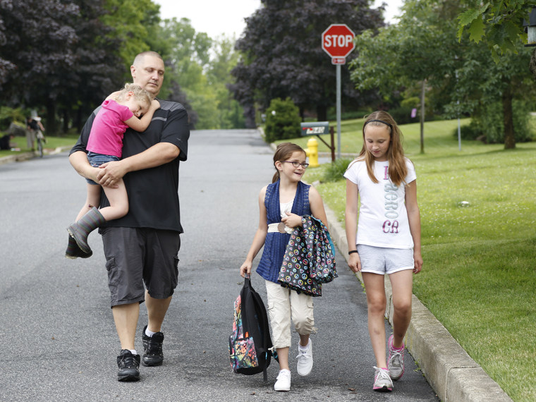 Carl Poff carries his daughter Joselyn, 4, after picking up his daughter Jillian, center right, from the bus stop near their home in Easton, Pa., on Thursday, June 14, 2013.