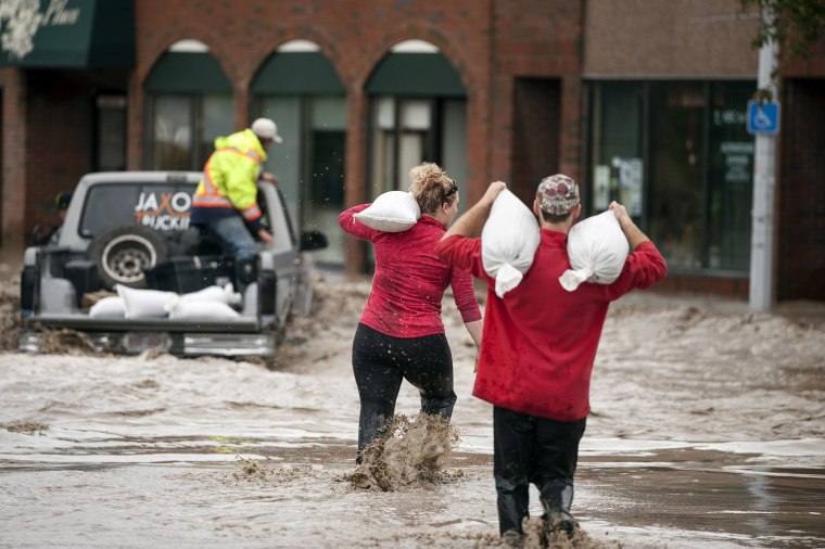 Image: Residents carrying sandbags wade through floodwater in High River in Alberta province