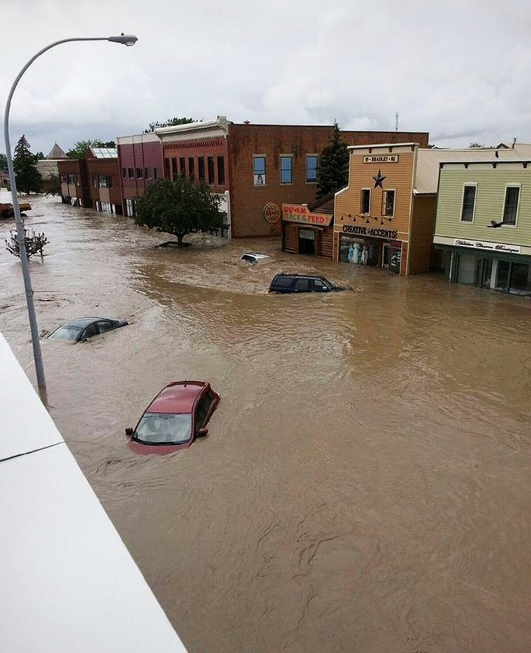 Image: Cars float in the water covering a downtown street in High River, Alberta
