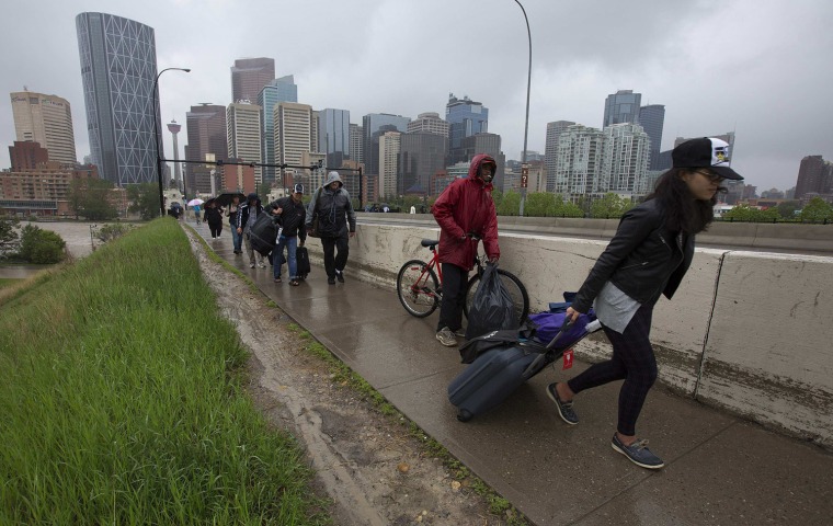 Image: Residents leave the flooding downtown core as new orders evacuating all of downtown were issued in Calgary