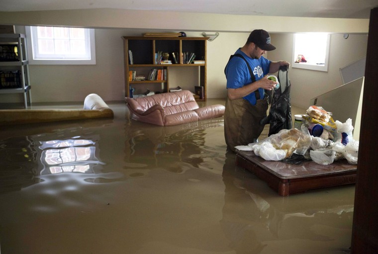 Image: Cody Scott throws food away from a freezer trapped in a flooded basement in the Elbow Park area of Calgary