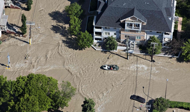 Image: A boat makes its way up a street after the Bow River overflowed its banks in a residential area of Calgary, Alberta