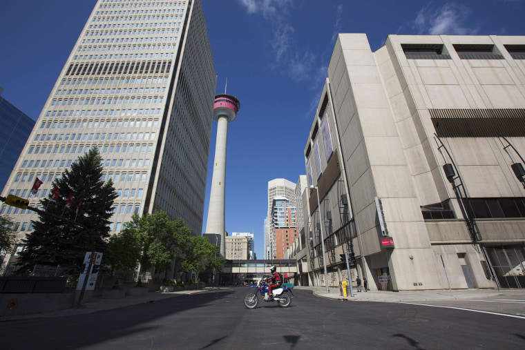 Image: A police office patrols deserted streets on dirt bike in downtown Calgary
