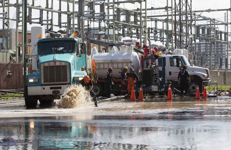 Image: Crew members from Enmax Energy city electric company pump water out of an electrical substation in Calgary