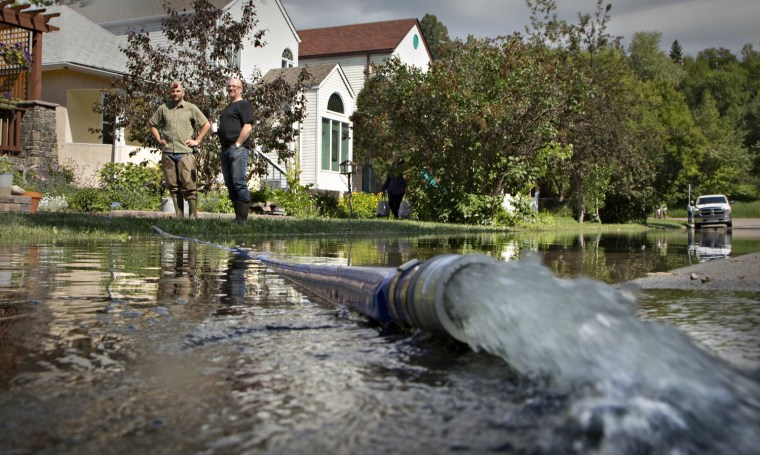 Image: Residents pump floodwater from their homes in Calgary